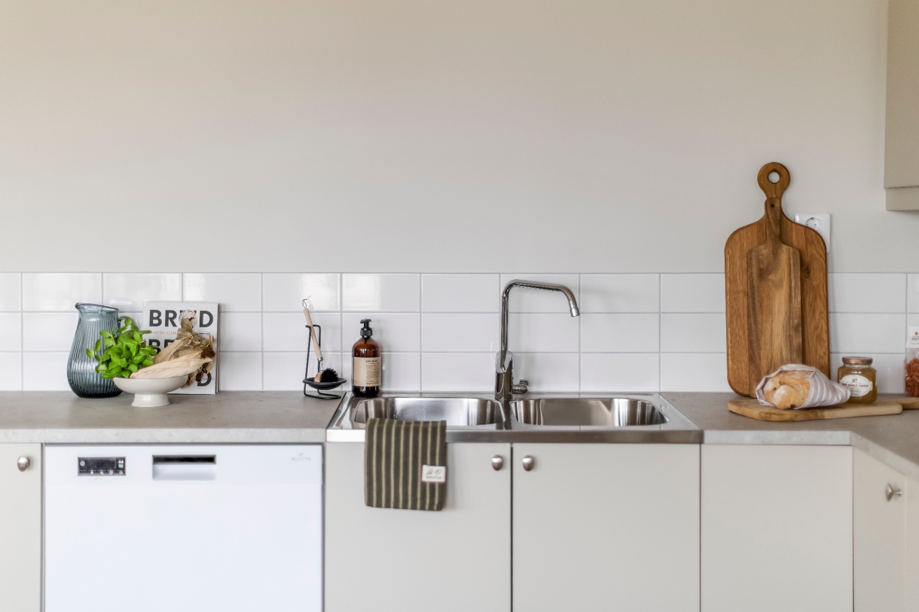 Kök med vit kakel, diskbänk och diskmaskin